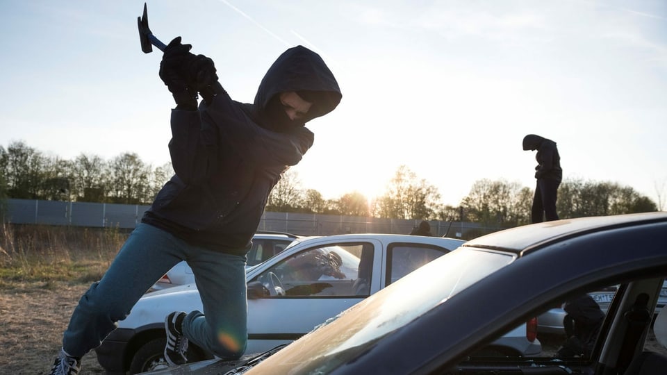 Ein Antifa-Aktivist schlägt mit einer Axt die Frontscheibe eines Wagens ein.