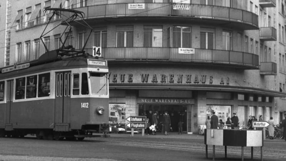 Schwarzweissbild eines Warenhauses, vor dem ein Tram vorbeifährt