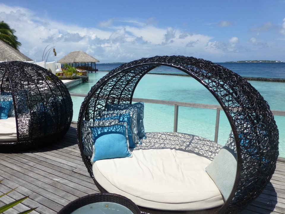 Lounge auf einem Holzsteg, dahinter das Meer.