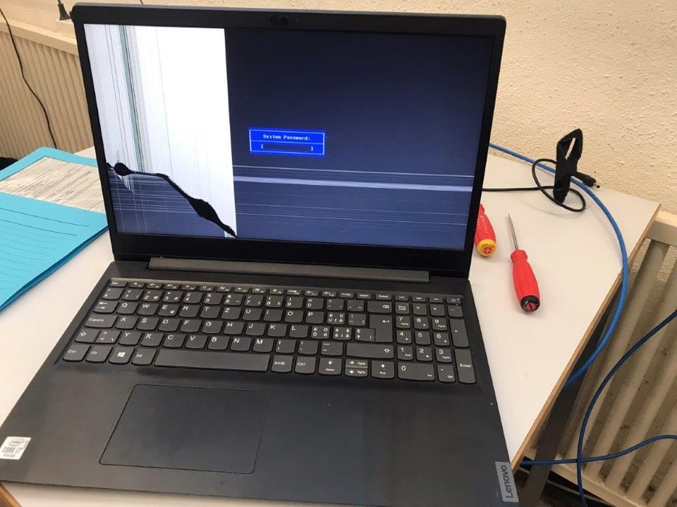 Ein Laptop steht aufgeklappt auf einen Tisch. Der Bildschirm ist kaputt, es flimmert und das Bild wird nicht geladen. 