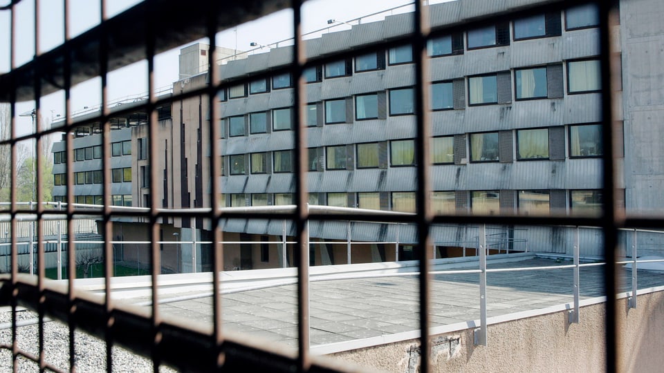Blick durch Gitter auf eine Gebäudefassade.