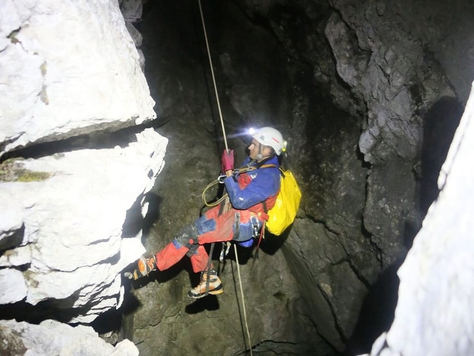Ein Mitglied der Bergwacht seilt sich in die Höhle hinunter. 