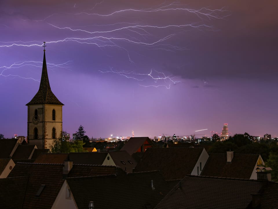 26. Juli Blitze am dunklen Himmel über der Dorfkirche von Muttenz.