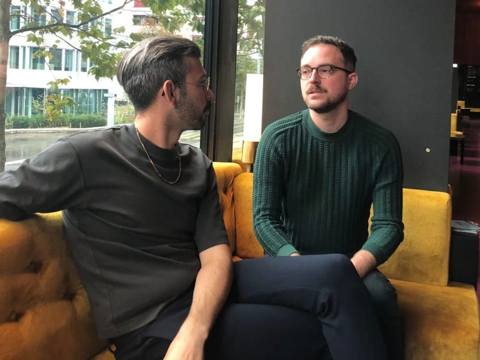 Opfer von Hate Crime Das homosexuelle Paar sitzt auf einem gelben Sofa in einem Café.
