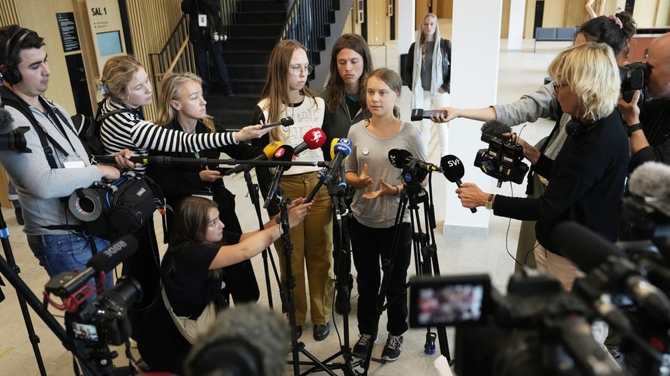 Greta Thunberg spricht vor vielen Mikrofons zu den Medien.