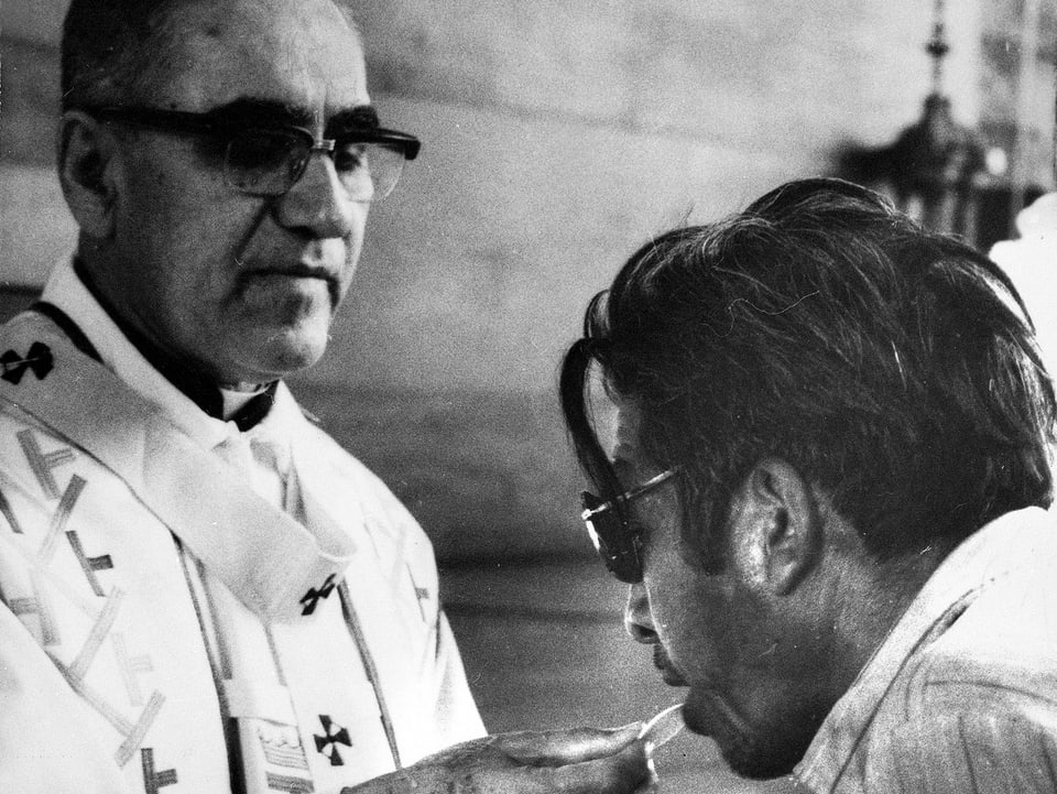 Ein Gläubiger empfängt von Priester Oscar Romero eine Hostie