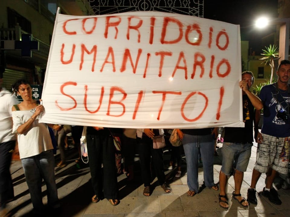 Menschen halten Banner mit der Aufschrift: «Corridoio Umanitario Subito!» hoch