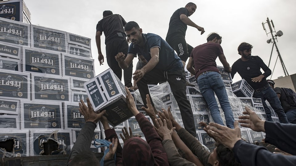 Personen verteilen Hilfsgüter an Menschen in Gaza.