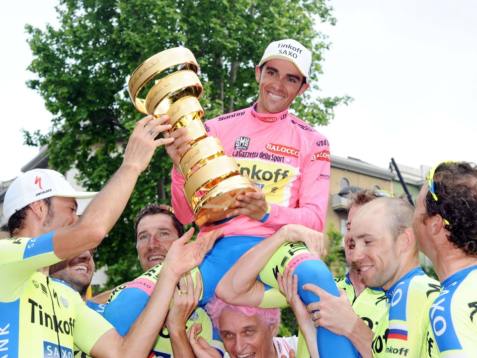Alberto Contador hält den Pokal in den Händen und wird von seinen Tinkoff-Teamkollegen auf den Schultern durch die Menge getragen.