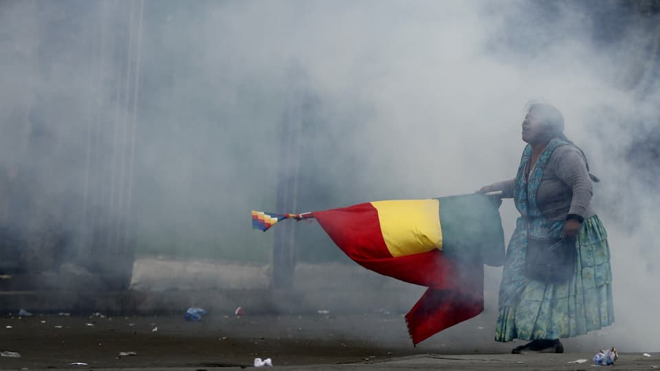 Eine Frau mit bolivianischer Flagge im Tränengas-Nebel