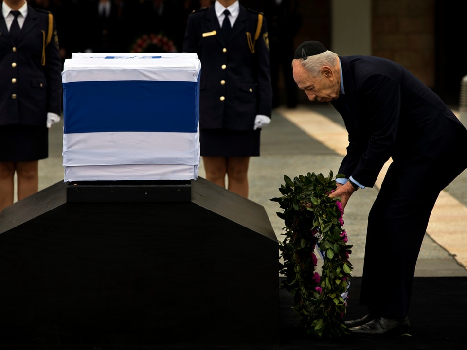 Peres legt Kranz an Sarg nieder