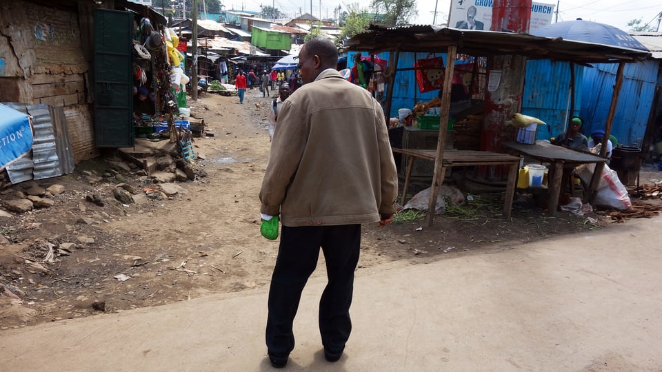 Ein Mann in einem Slum, in der Hand eine Flasche.