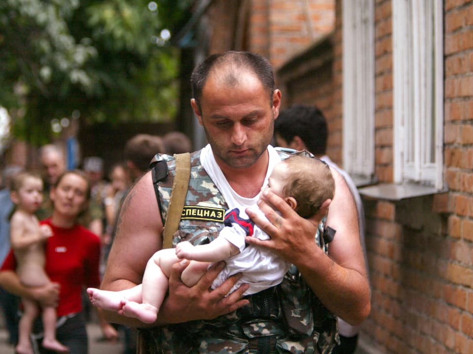 Ein russischer Polizist hält ein Baby in den Armen