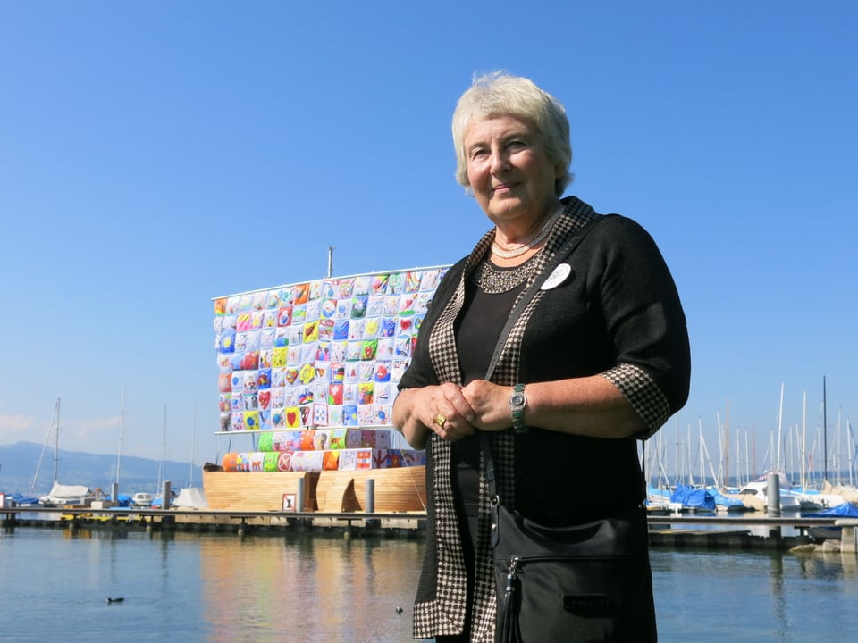 Emilia Kabakov steht vor einem Schiff mit buntem Segel.