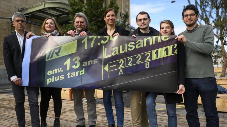 Lausannes Politiker halten ein Plakat vor dem Bahnhof Lausanne. 