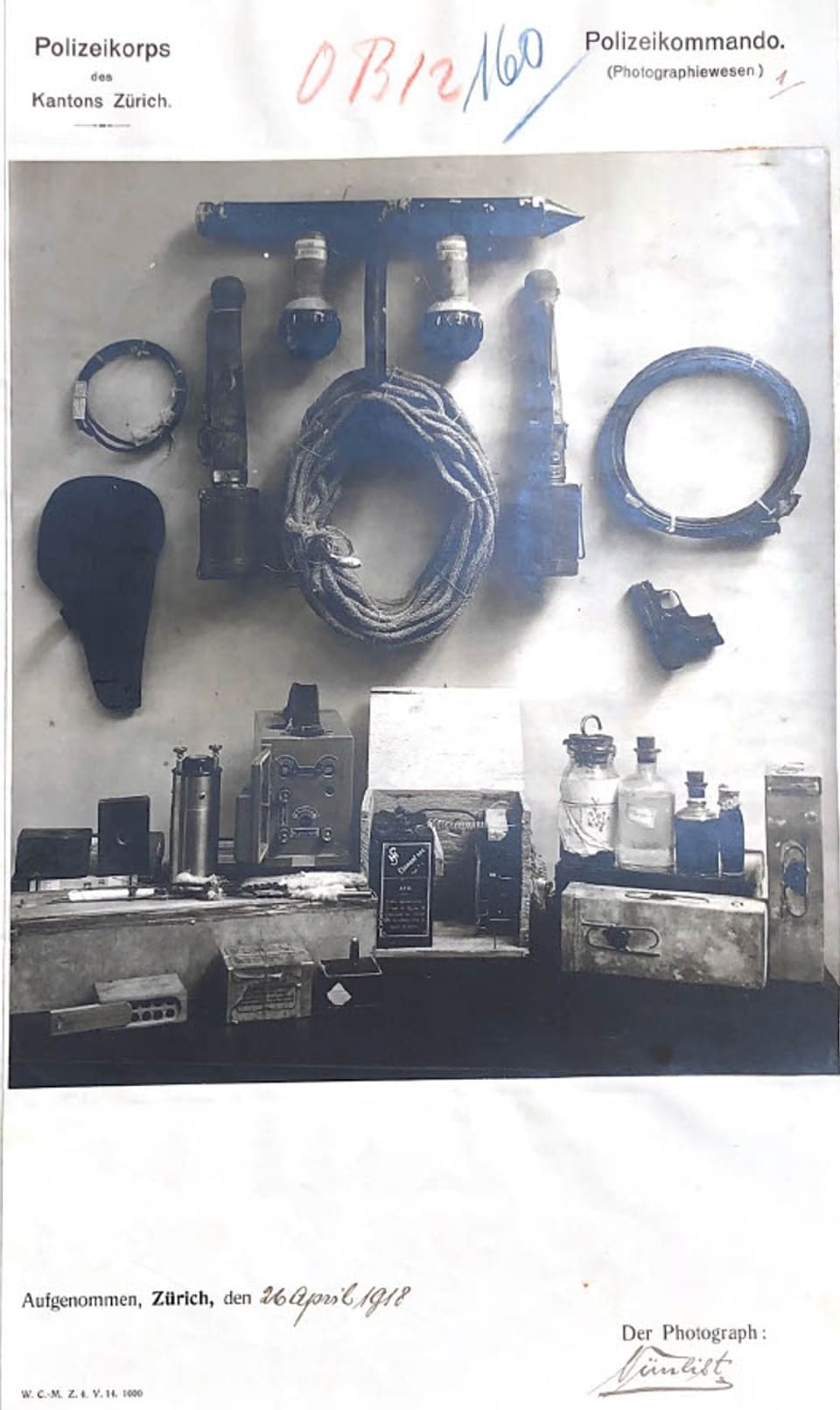 Archivfoto verschiedener Waffen wie Handgranaten, Spiritus, Pistolen und Seilen, für ein Polizeifoto arrangiert.