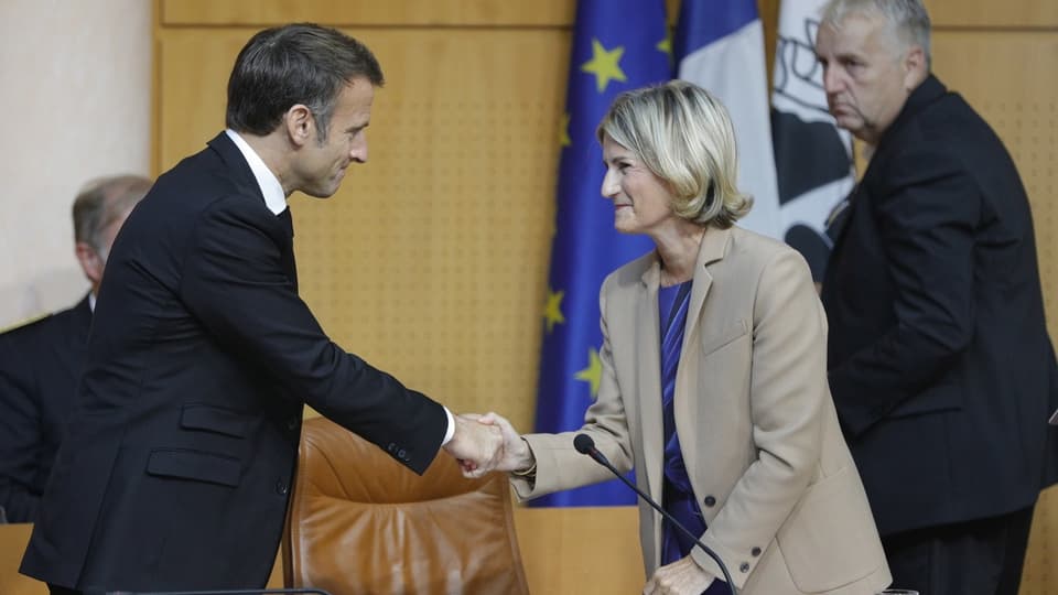 Frankreichs Präsident Macron schüttelt Maupertuis, der Präsidentin der Versammlung von Korsika, die Hand.