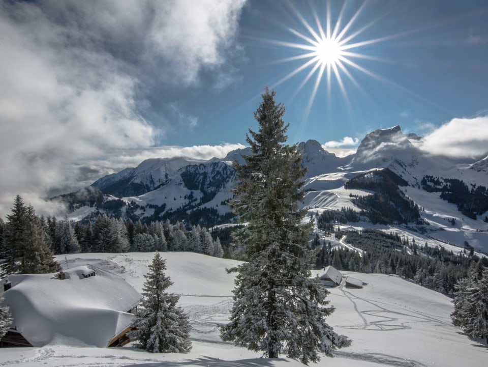 Tiefverschneite Winterlandschaft mit Sonnenschein, blauem Himmel und einigen Wolken.