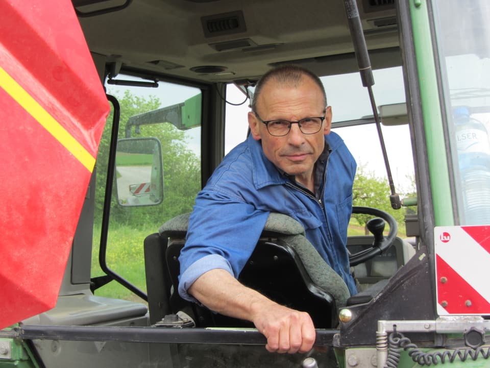 Ein Mann mit Igelifrisur und Brille in einem Traktor