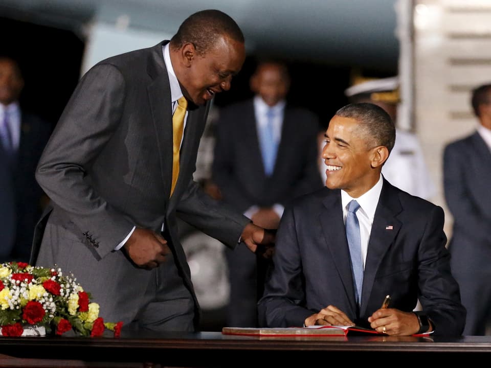 Obama schreibt ins Gästebuch. Lachend unterhält er sich dabei mit Kenias Präsidenten Uhuru Kenyatta.