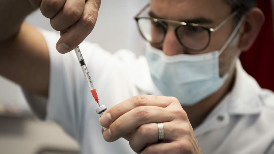 Ein Arzt zieht eine Impfspritze auf.