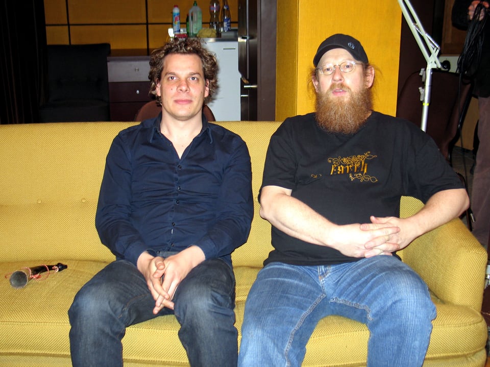 Zwei Männer sitzen auf einem gelben Sofa