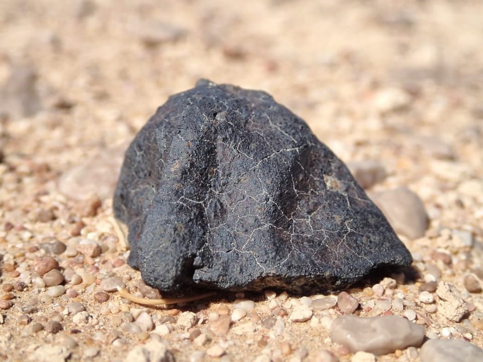 Meteorit liegt auf sandigem Boden