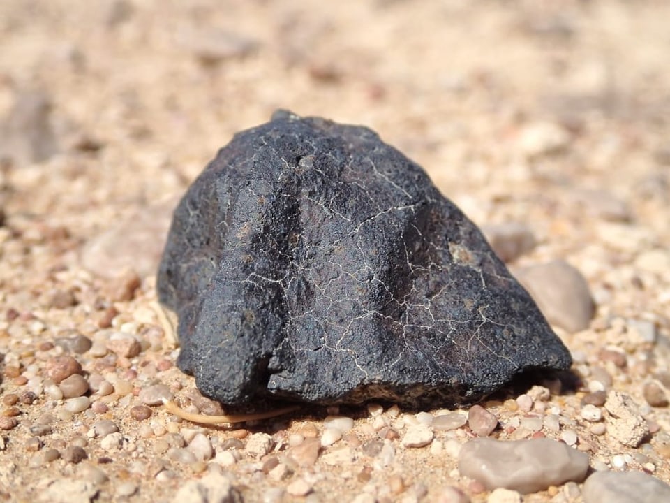 Meteorit liegt auf sandigem Boden