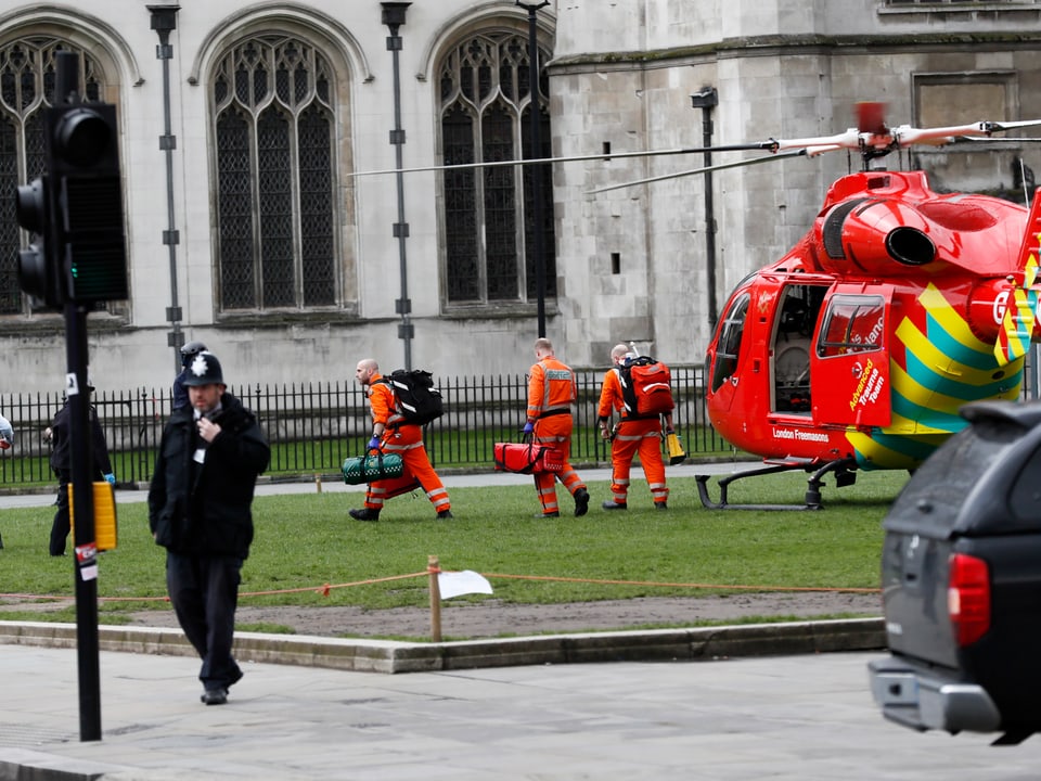 Ein roter Helikopter steht am Boden, Rettungskräfte in rot gekleidet steigen aus