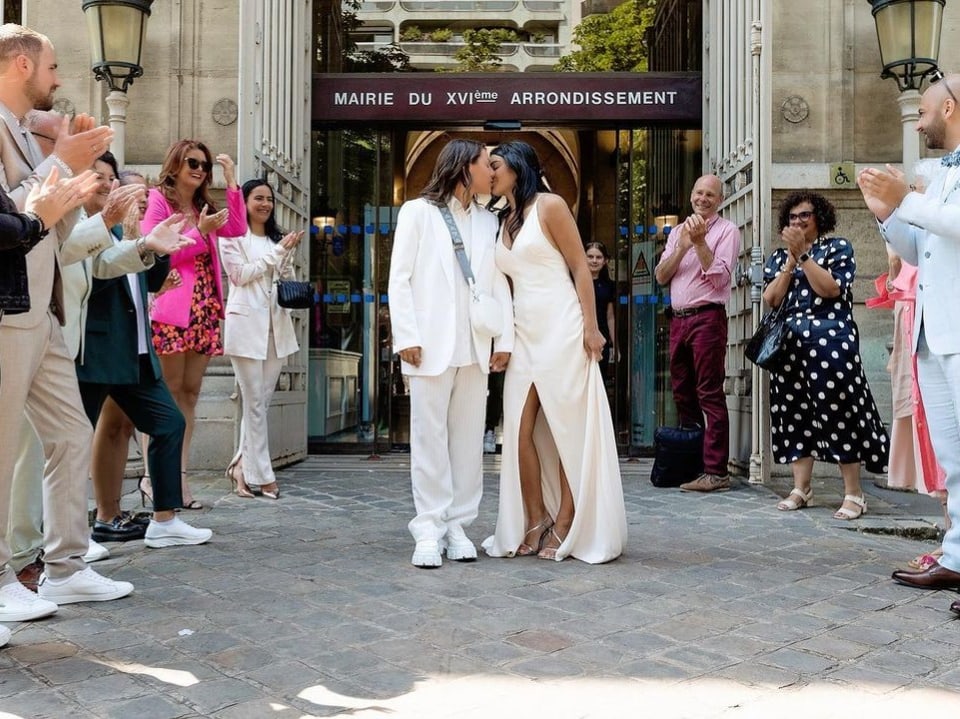 Ramona Bachmann und Charlotte Baret küssen sich vor dem «Mairie du arrondisement» in Paris umgeben von Familie.