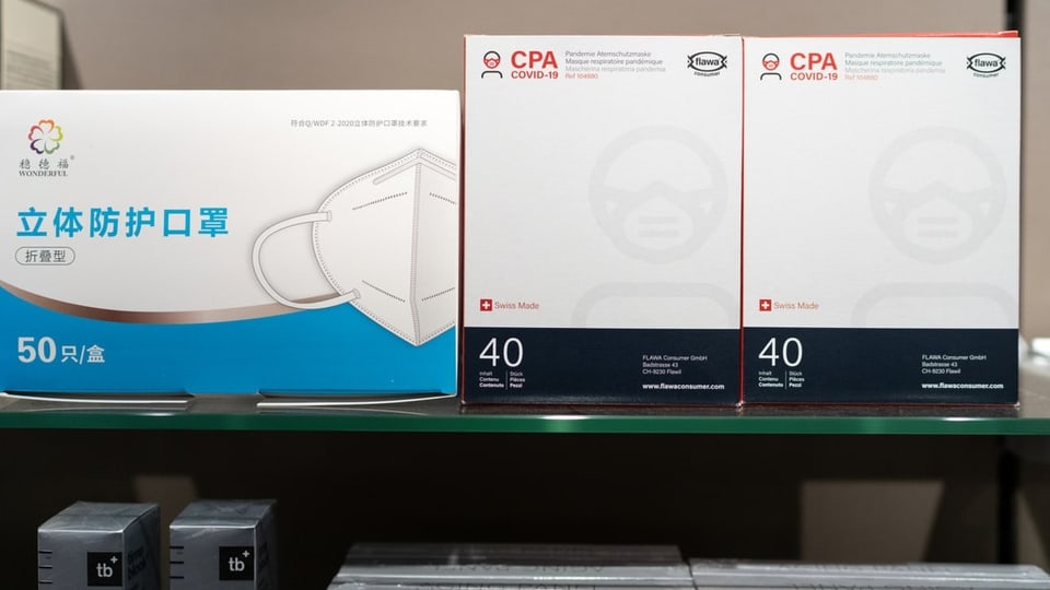 Eine Schachtel Masken aus China steht neben zwei Schachteln der Schweizer Marke Flawa.