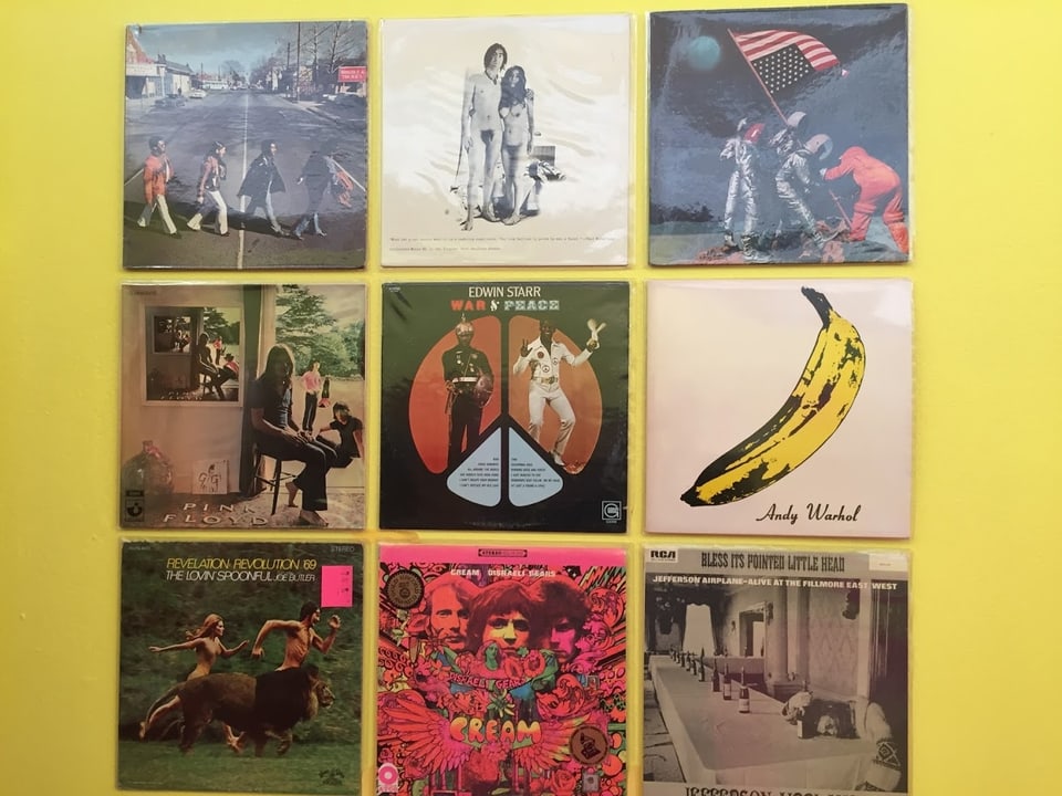 Ausstellung von Vinylplatten aus den 60er-Jahren. Diese hängen an einer gelben Wand. Zu sehen sind die Covers der Platten.