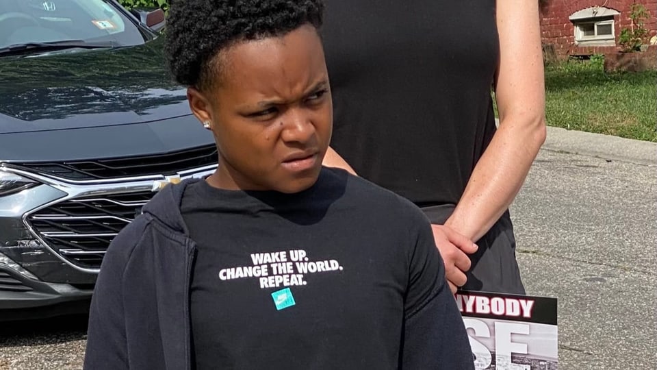 Eine schwarze junge Frau trägt ein T-Shit mit der Aufschrift: «Wake up. Change the World. Repeat.»..