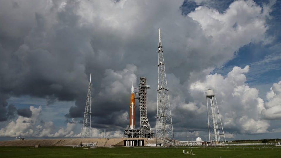 Die Rakete ist am Launchpad befestigt, während dahinter sich ein Unwetter anbahnt.