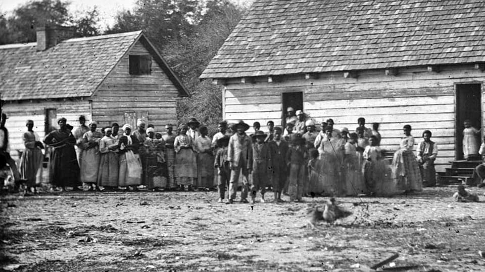 Dutzende Sklaven stehen vor zwei Häusern