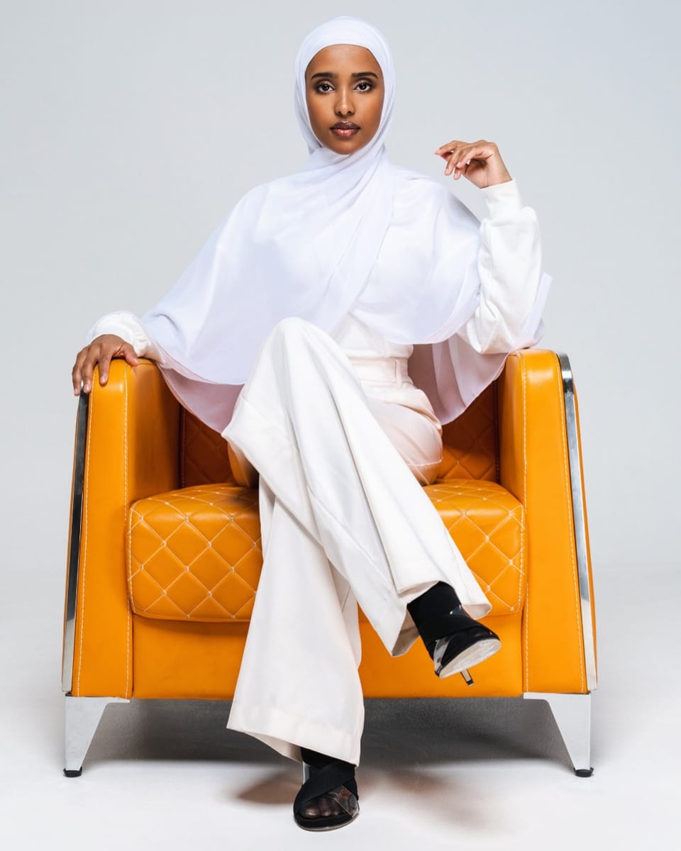 Hanan sitzt auf einem Sofa in einem weissen Hijab.