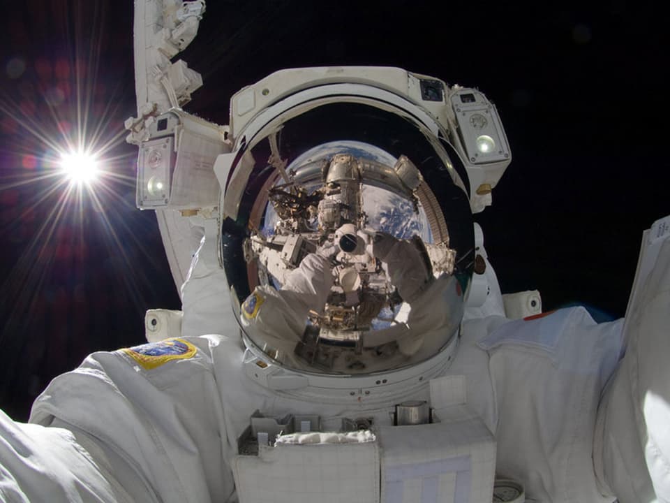 Nasa-Astronaut Aki Hoshide fotografierte sich selbst, die Erde wird auf dem Visir seines Helmes gespiegelt.