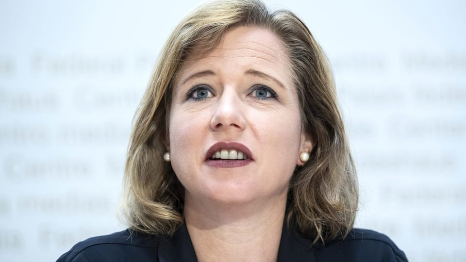 Christa Markwalder mit braun-blondem mittellangem Haar und Perlohringen.