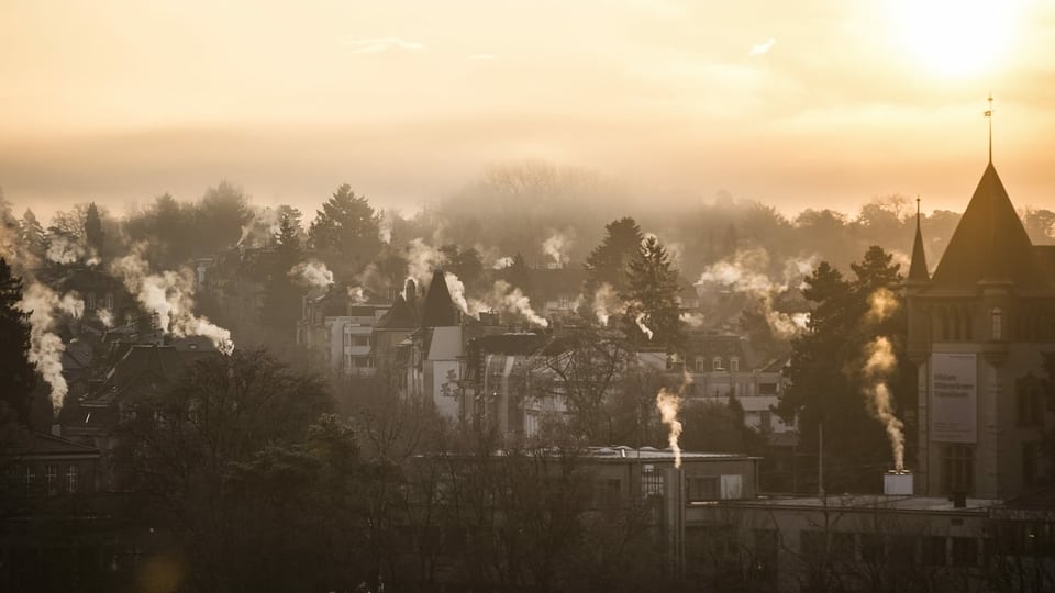 Winterlich-morendlicher Blick über Bern, die Heizungsschlote der Häuser rauchen.