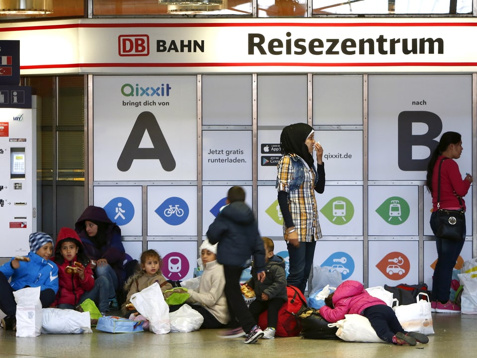 Mehrere Kinder und drei Frauen halten sich inmitten des Bahnhofs auf. 