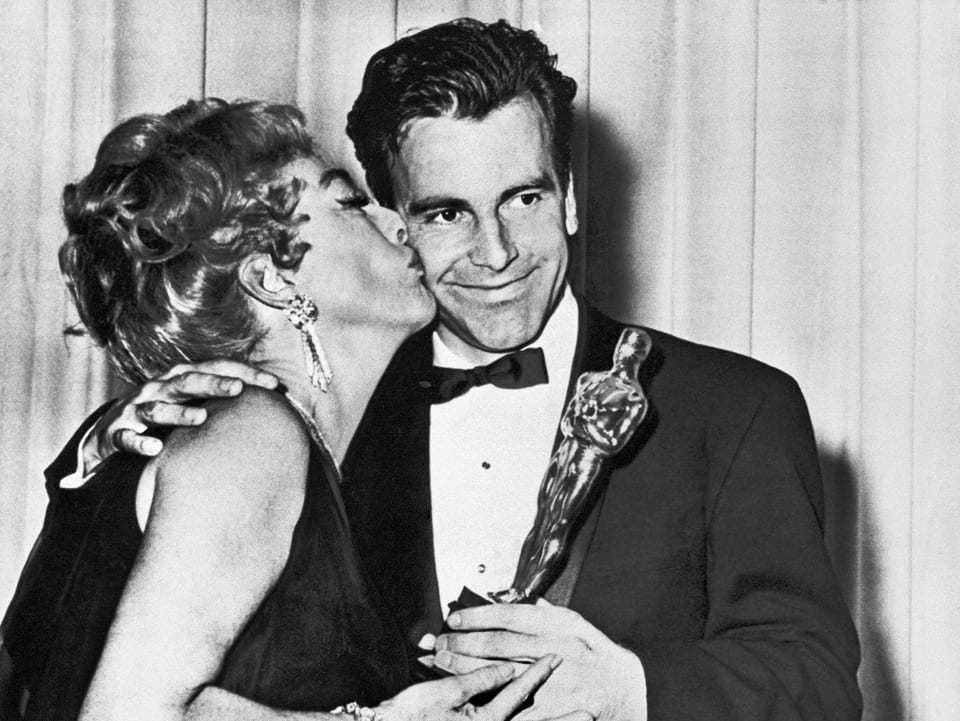 Schauspielerin Joan Crawford küsst den lächelnden Maximilian Schell mit der Oscar-Statue in der Hand.