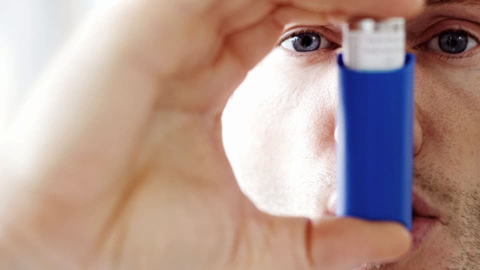 Mann hält sich einen Asthma-Inhalator in den Mund