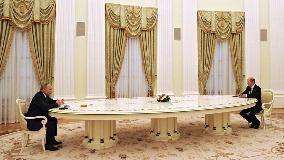 Putin und Scholz sitzen sich an einem sehr langen Tisch gegenüber.