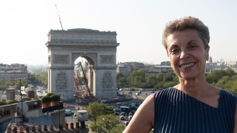 Eine Frau, im Hintergrund der Arc de Triomphe in Paris