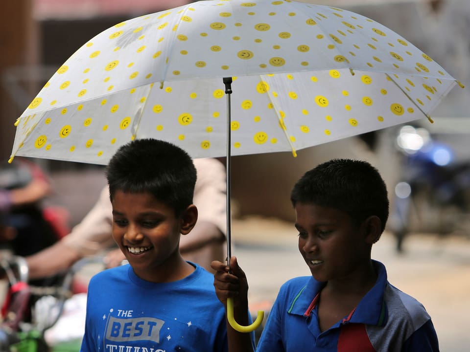 Zwei Schuljungen gehen unter einem Schirm