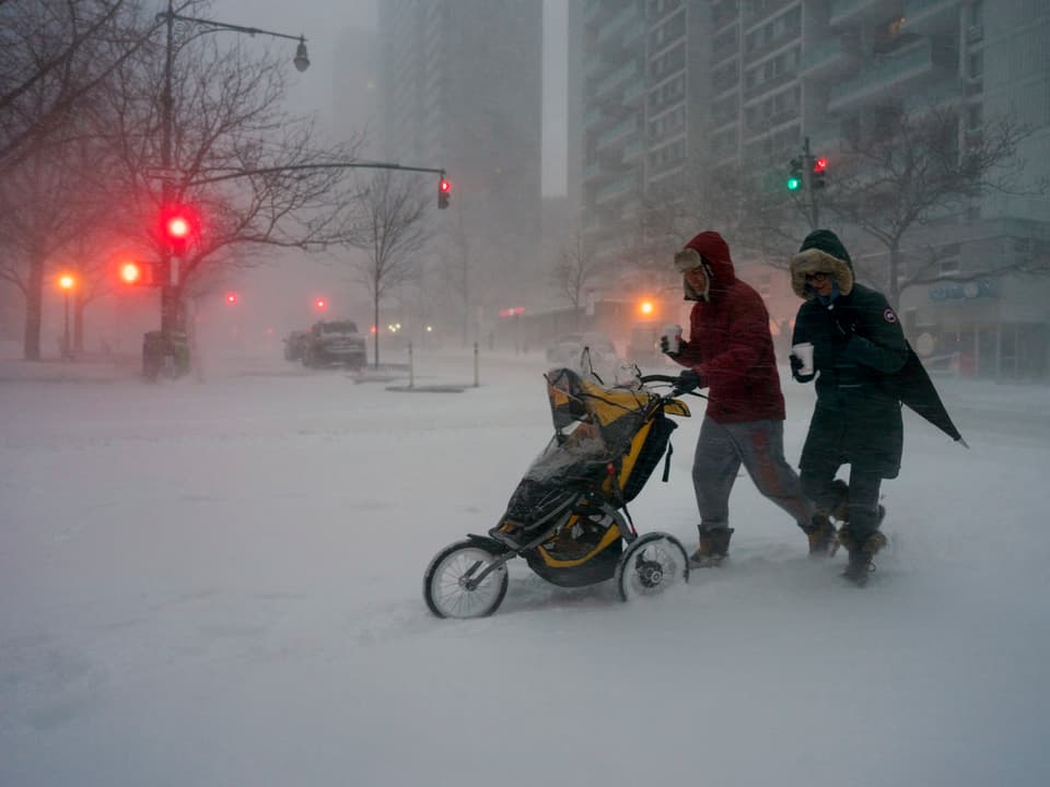 Eine Familie mit Kinderwagen kämpft sich durch den Schnee