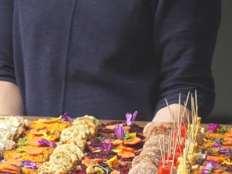 Mann präsentiert eine Platte mit schön dekorierten Apéro-Häppchen