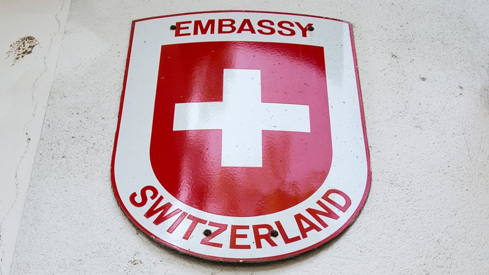 «Embassy Switzerland»-Schild mit einem Schweizerkreuz an einer Wand.