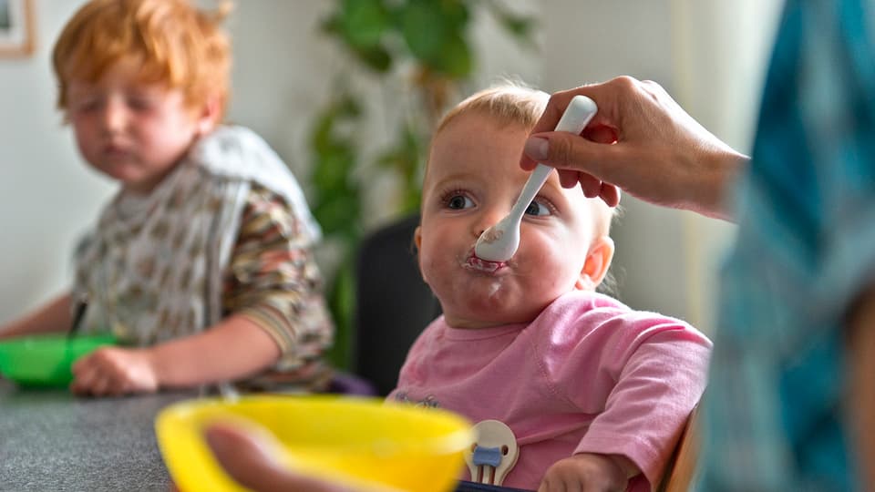 Eine Mutter füttert ihr Baby mit Brei. 