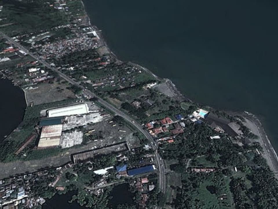 Ein Luftbild von Tacloban vor dem Sturm: Grüne Bäume und Wiesen, grünes Meer, intakte Strassen und Häuser. 